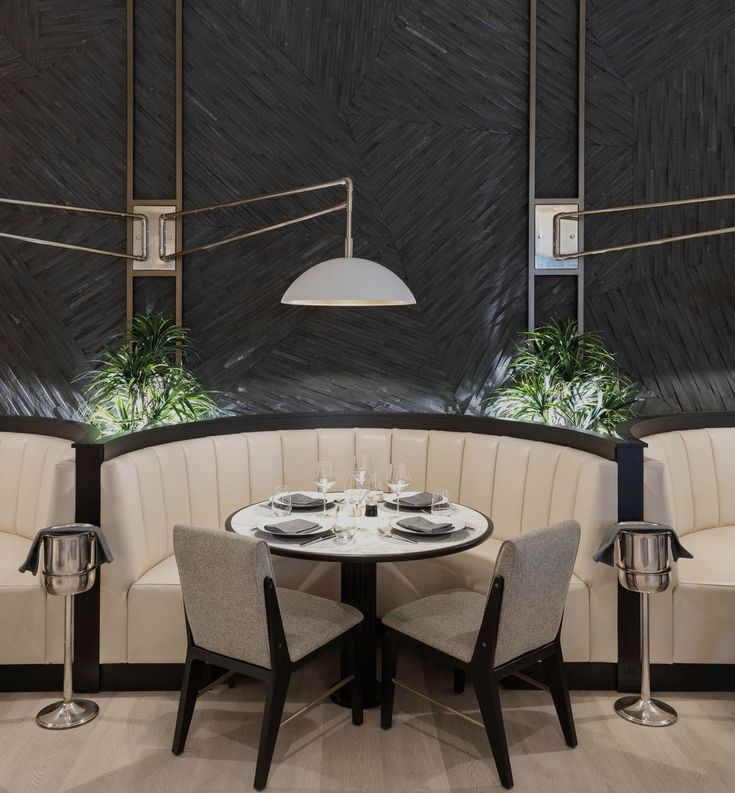 a table with four chairs around it in front of a black and white wallpaper