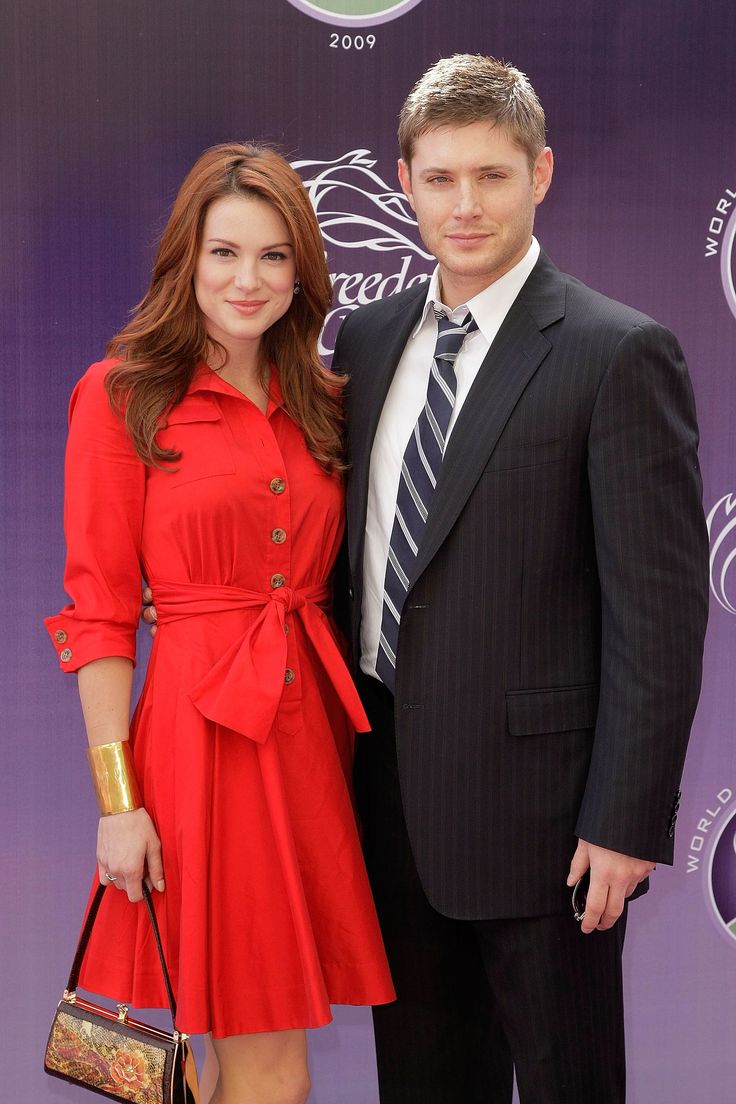 a man in a suit and tie standing next to a woman wearing a red dress