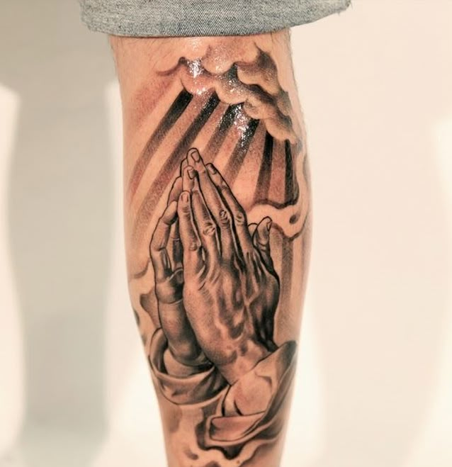 a person with a tattoo on their leg that has praying hands in front of him