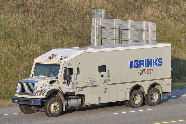 the truck is driving down the road by the grass