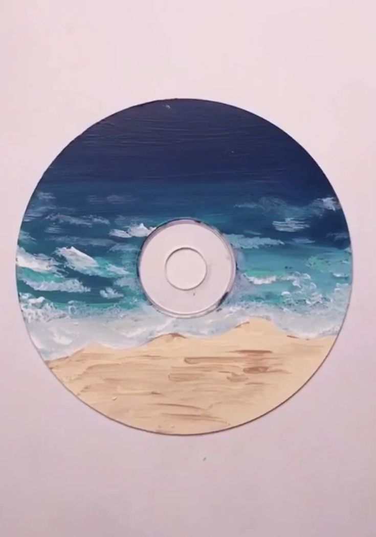 a cd that is sitting on top of a white surface with blue and green water in the background