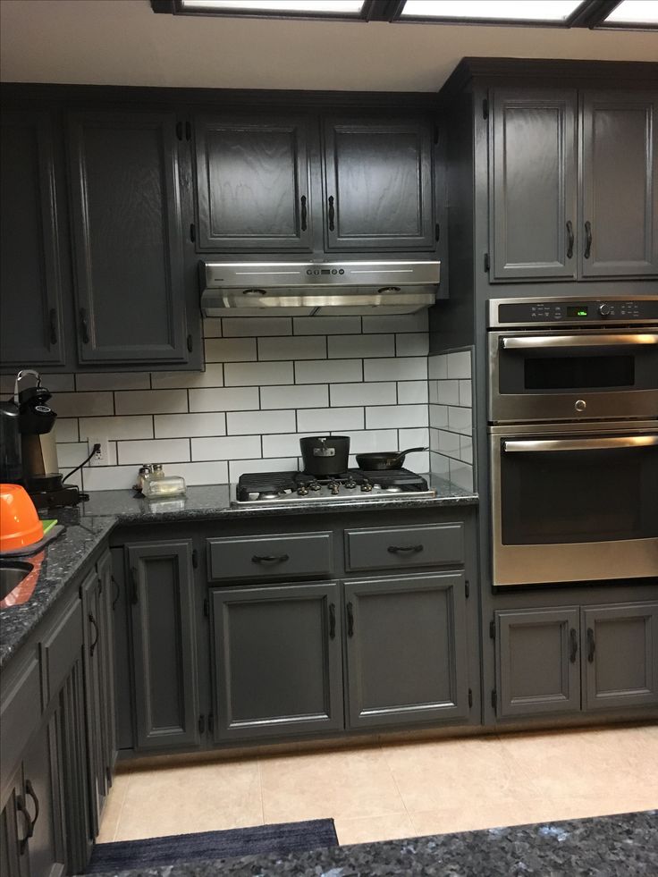 a kitchen with gray cabinets and black counter tops, stainless steel appliances and an oven