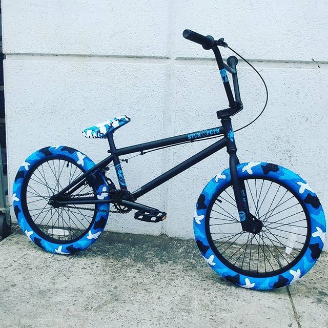 a black and blue bike with stars on the rims is parked in front of a building