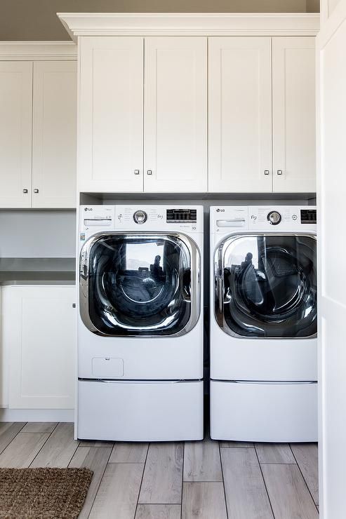 a washer and dryer in a white laundry room with wood flooring on the side