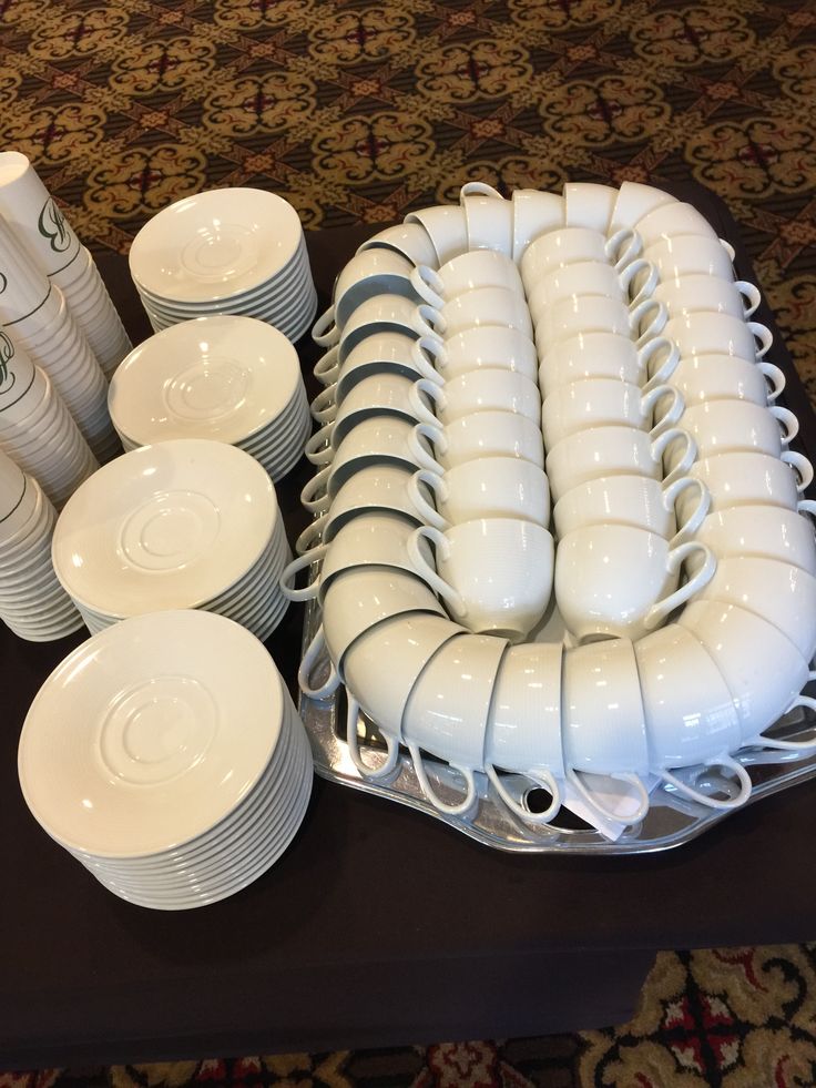 a table topped with lots of white plates and cups on top of a black table