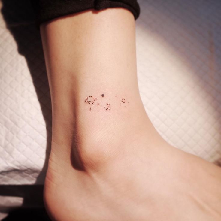 a small tattoo on the ankle of a woman's foot with planets and stars