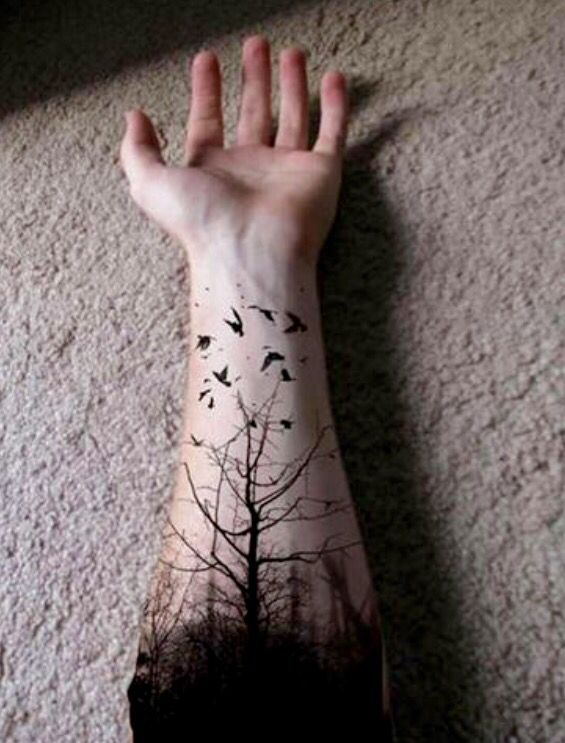 a person's arm with a tree and birds on it, in front of a wall