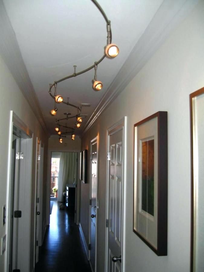 a long hallway with lights hanging from the ceiling and pictures on the wall above it