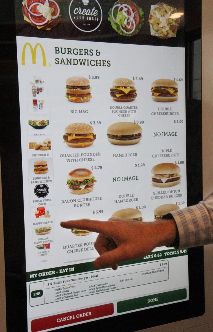 a man pointing at a menu for burgers and sandwiches