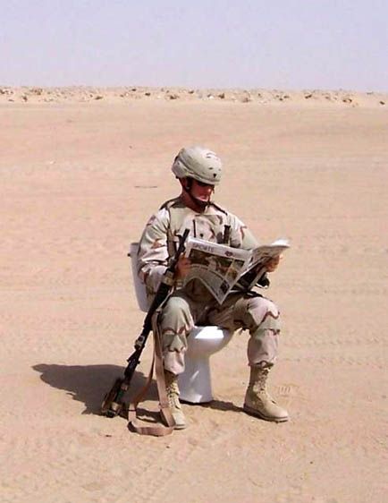 a man sitting on top of a toilet in the desert