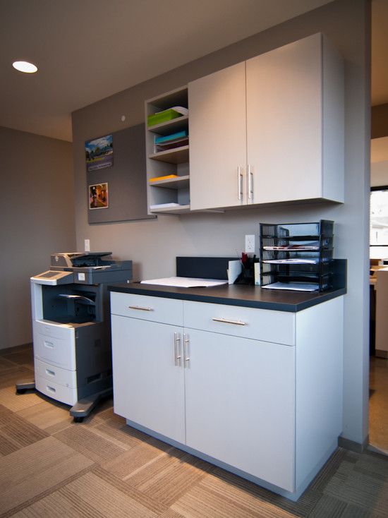 an office with white cabinets and black counter tops, including a printer on the floor