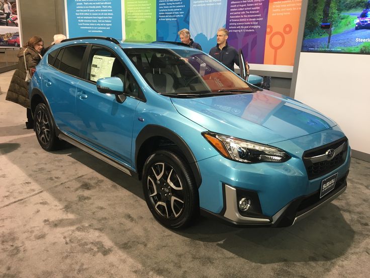 a blue subarunt is on display in a showroom with people looking at it