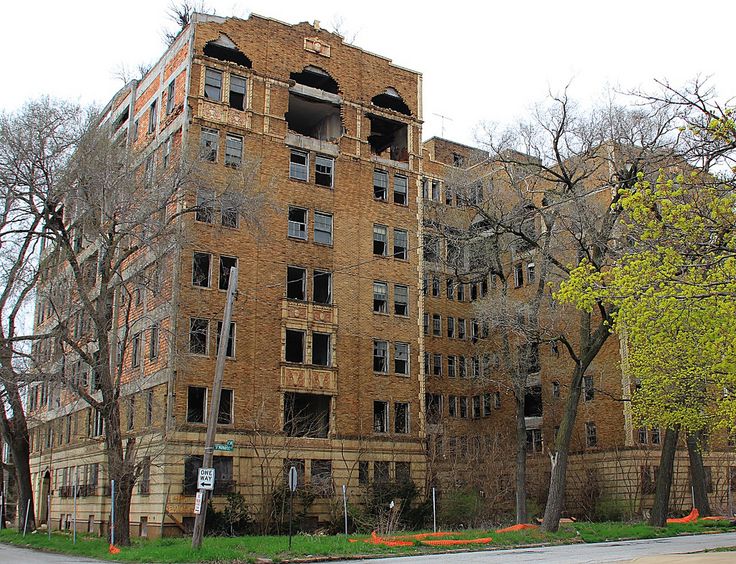 an old brick building with broken windows on the side and trees in front of it