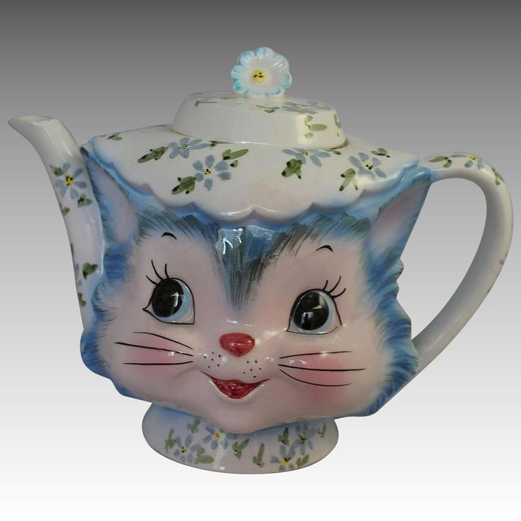 a ceramic teapot with a cat's face painted on the front and sides