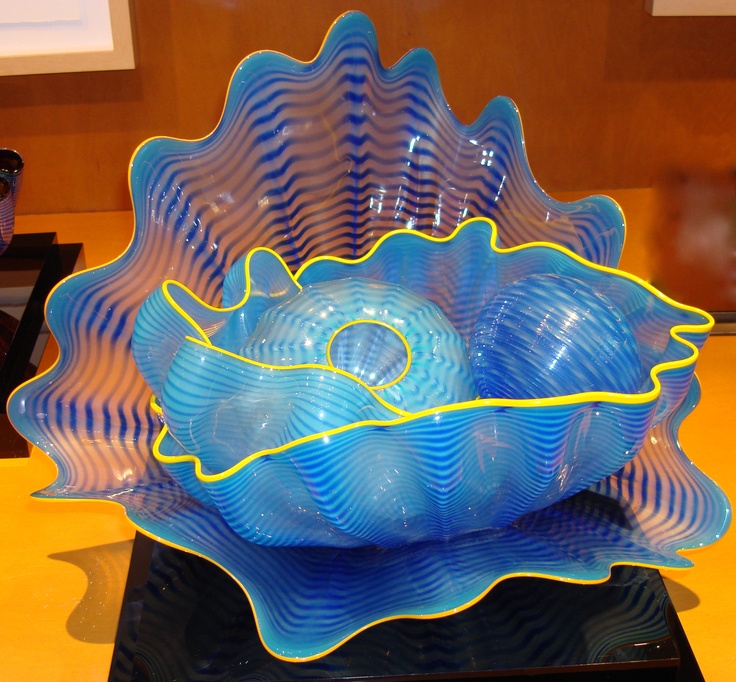 a blue glass bowl sitting on top of a black table next to a cell phone