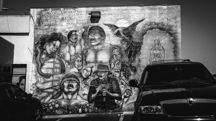 a black and white photo of some cars parked in front of a building with graffiti on it