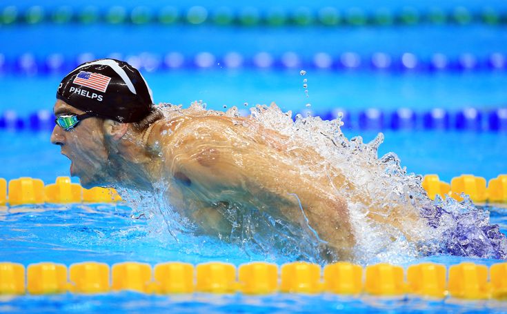 a man swimming in a pool with an american flag on his cap and goggles