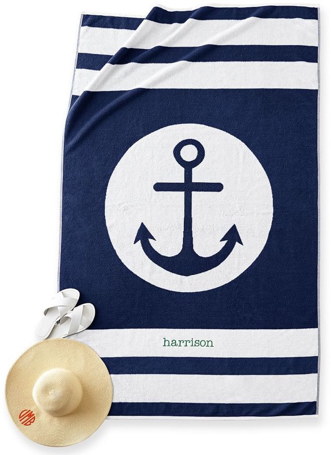 a towel with an anchor on it next to a straw hat and seashells