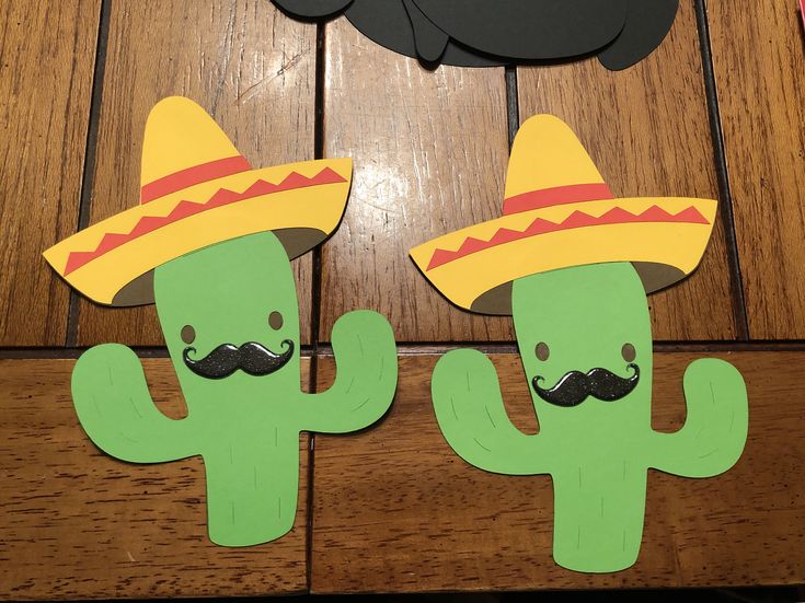 two paper cactus with sombreros and mustaches on their heads sitting next to each other