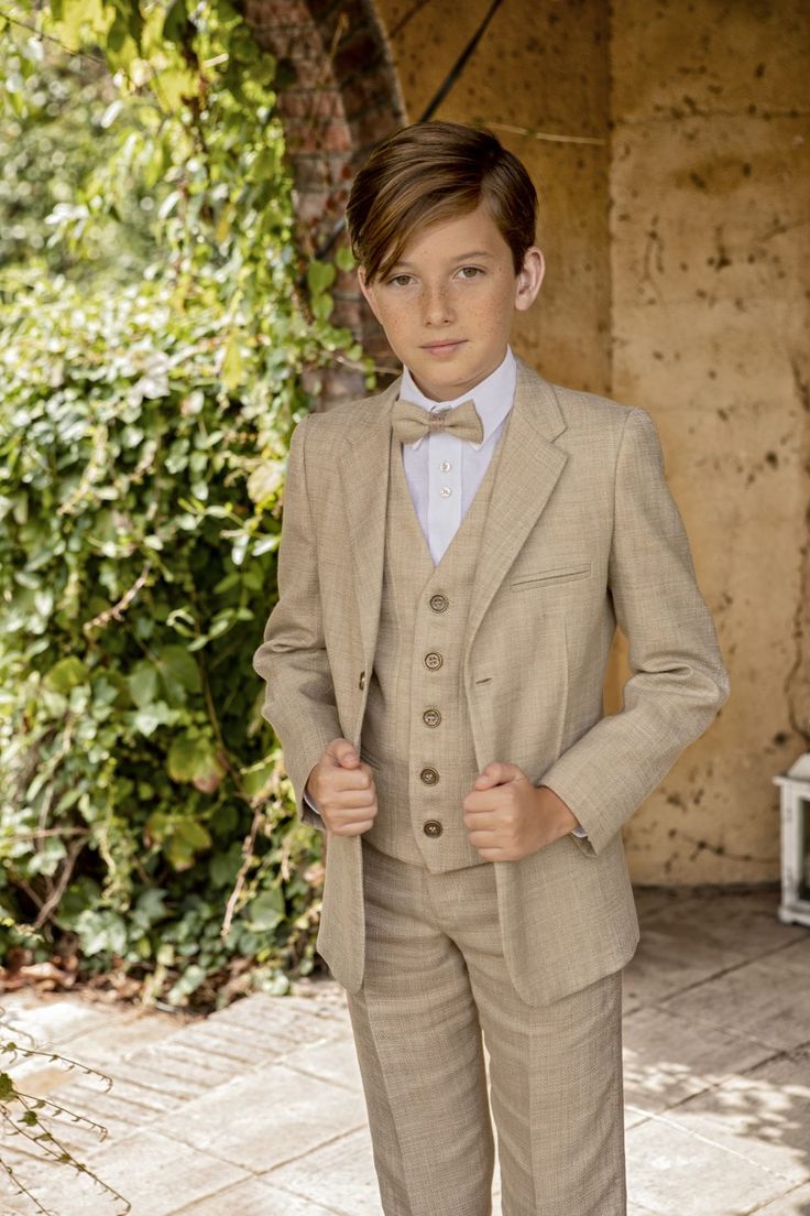 A Young Boy In A Suit And Bow Tie Posing For The Camera With His Hands 