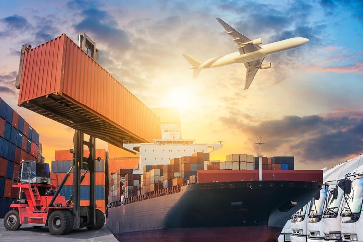 an airplane is flying over shipping containers and trucks at the dock in front of a cargo ship