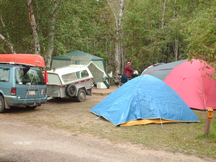 several tents are set up on the side of a road near a truck and camper van