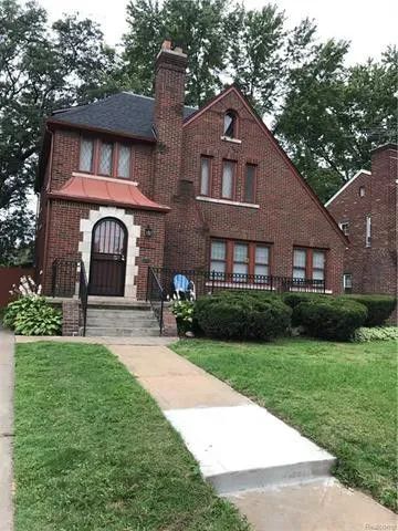 a large brick house sitting on top of a lush green field next to a sidewalk