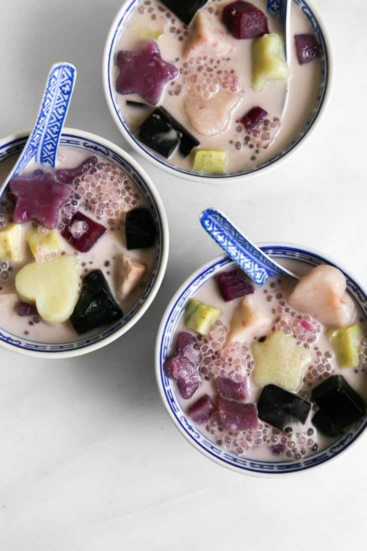 three bowls filled with fruit and yogurt on top of a white countertop