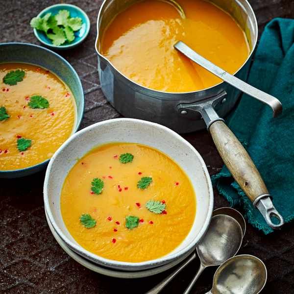 three bowls of soup with spoons on a table