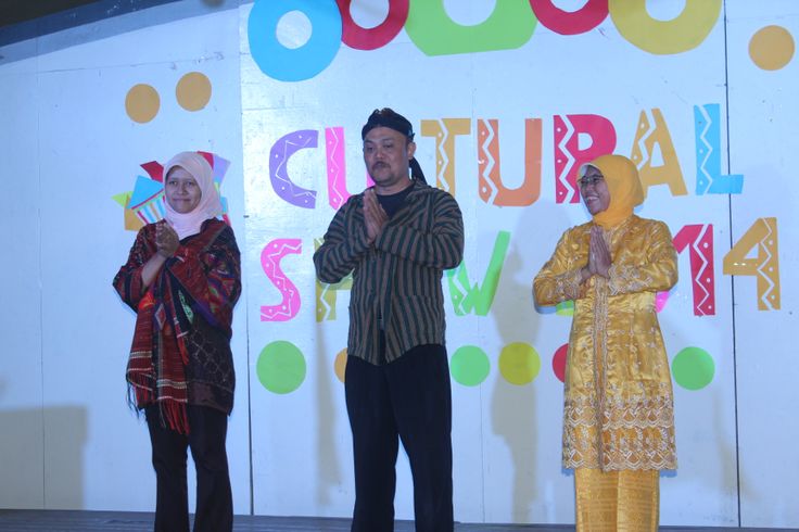 three people standing on stage in front of a sign