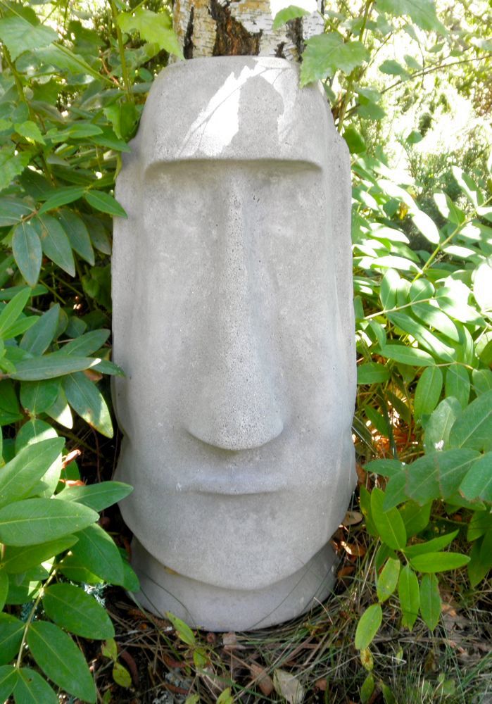 a stone head is sitting in the bushes