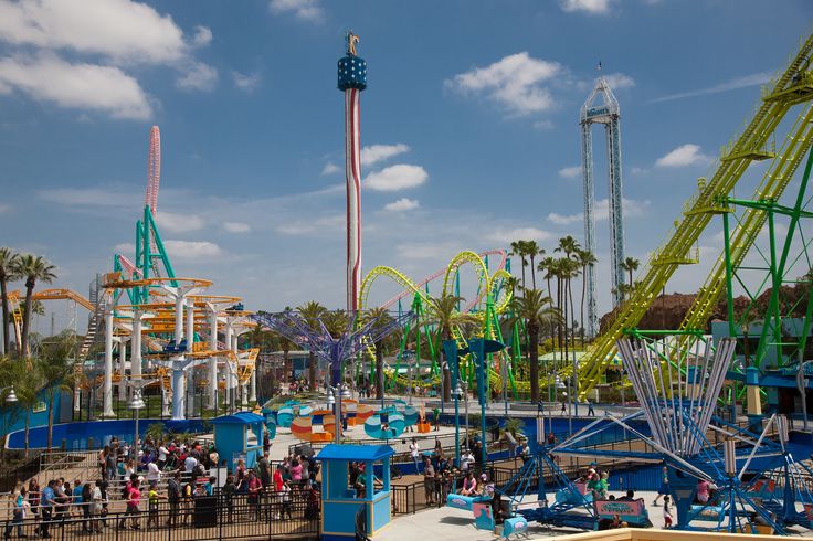 an amusement park with several rides and people on the ride area, including roller coasters