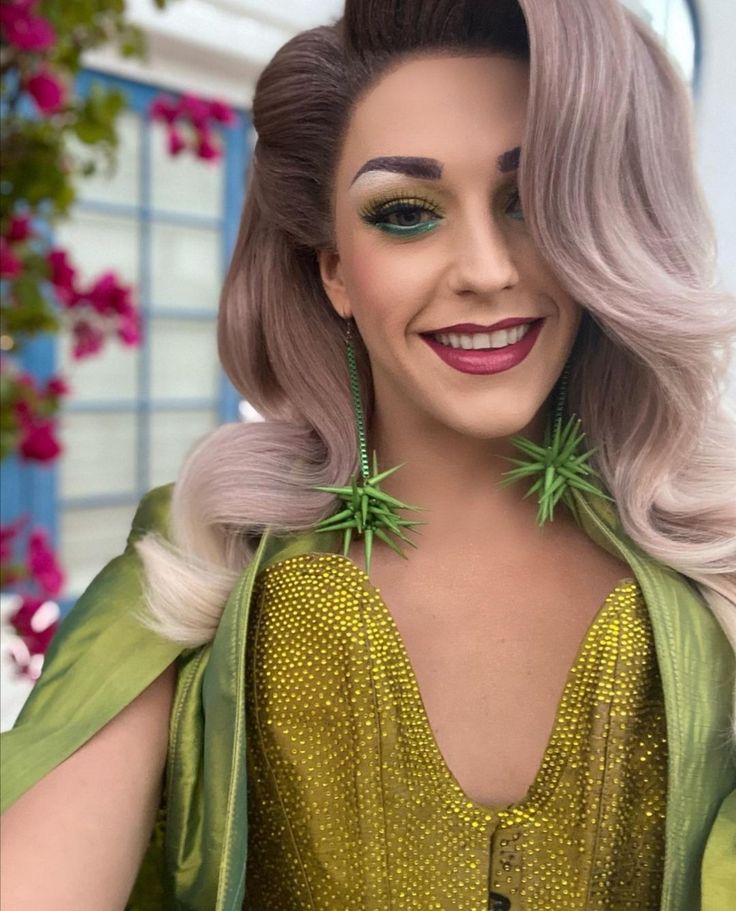 a woman with grey hair and green dress smiling at the camera while wearing large earrings