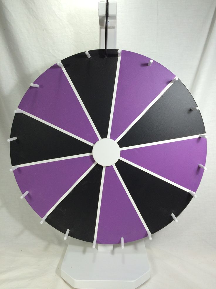 a large purple and black clock on a white base with holes in the middle to show time