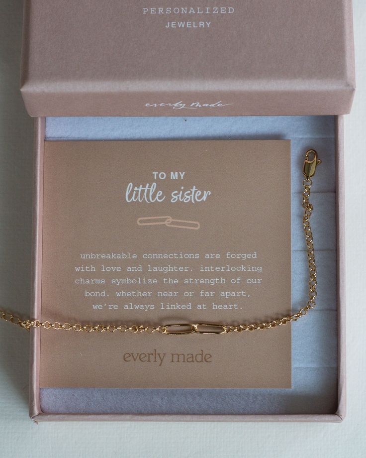 a little sister bracelet in a pink box with a gold plated chain attached to it