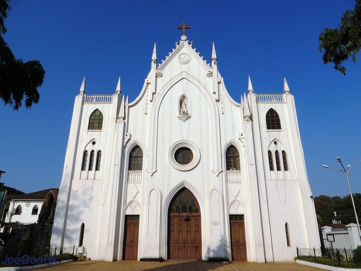 a large white church with a cross on it's steeple and two doors