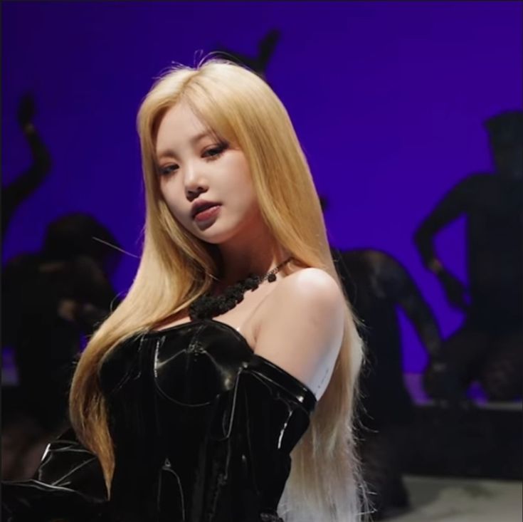 a woman with long blonde hair standing in front of a purple background wearing a corset