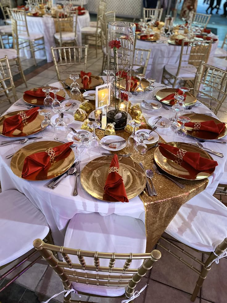 the table is set with gold plates and red napkins