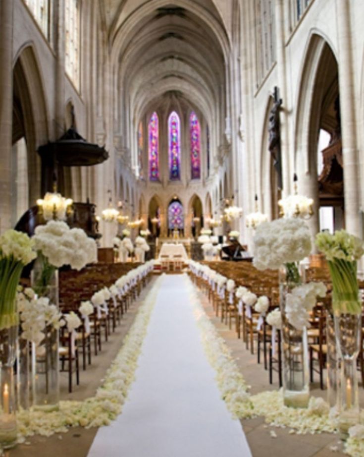 the aisle is decorated with white flowers and candles