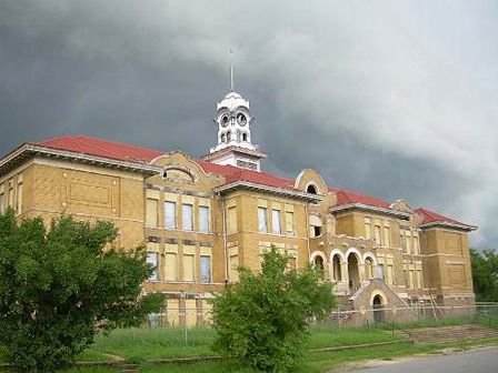 an old building with a clock tower on top and cloudy skies in the back ground