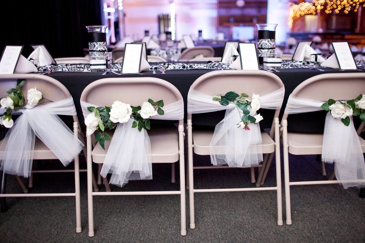 the tables are decorated with white flowers and tulle sashes