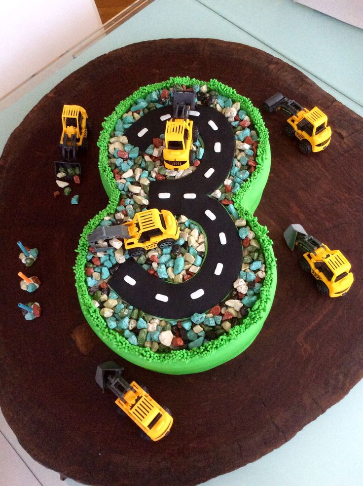 there is a birthday cake with cars and trucks on the road in front of it