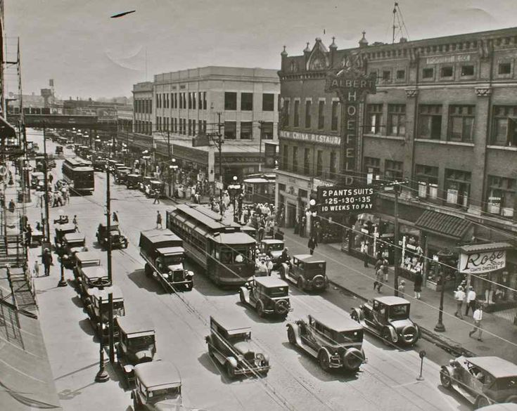 an old black and white photo of cars driving down the street