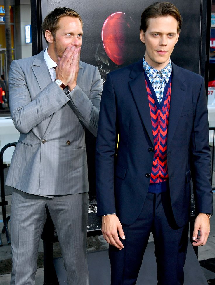 two men standing next to each other in front of a movie poster at an event