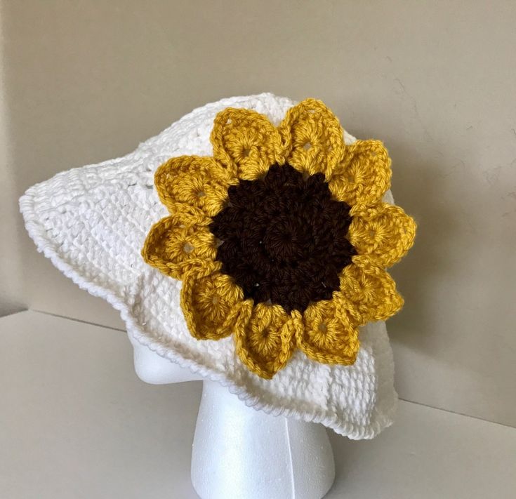 a crocheted sunflower hat on a white mannequin headdress