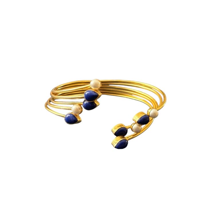 The Jahnavi Bracelet embodies the vibrant essence of the River Ganga with its luxurious blend of contrasting stones set in gold. Featuring custom-cut Lapis lazuli and ivory pearls, it creates a regal and dynamic accessory. Elegant Adjustable Stones Bangle, Elegant Lapis Lazuli Gemstone Bracelets, Elegant Adjustable Bangle With Stones, Luxury Natural Stones Bangle, Luxury Gold Bracelets With Gemstone Accents, Elegant Natural Stones Cuff Bangle Bracelet, Elegant Cuff Bracelet With Natural Stones, Elegant Natural Stone Cuff Bangle, Elegant Natural Stones Cuff Bracelet