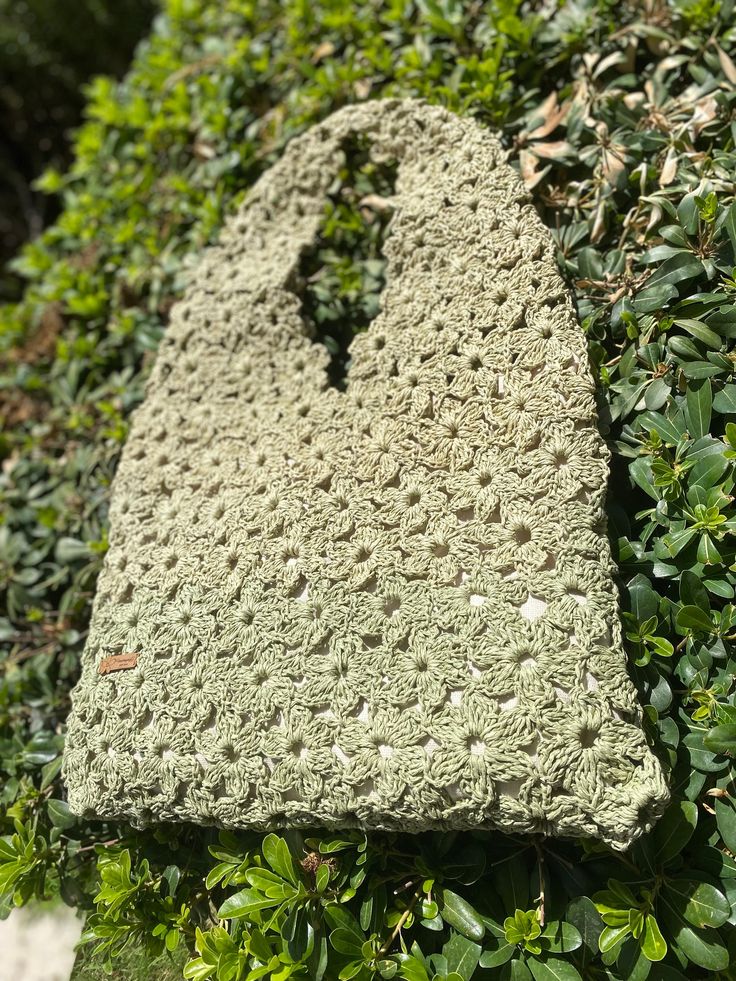 a crocheted bag sitting on top of a bush