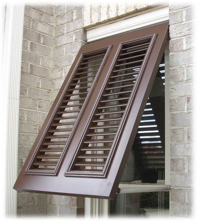 an open window with brown shutters on the side of a brick building in front of it