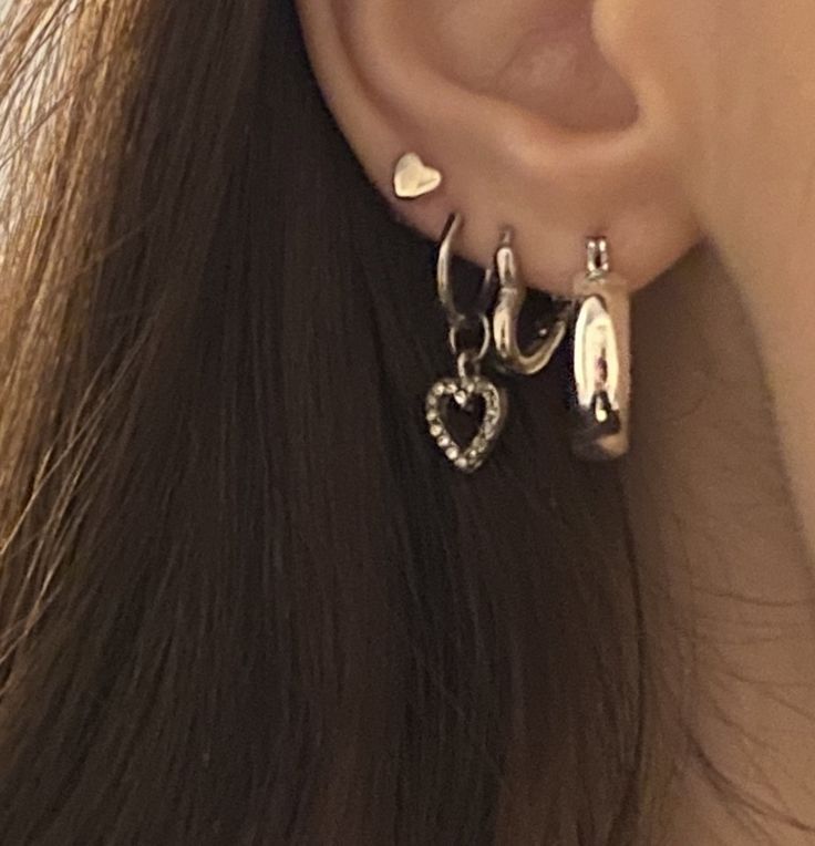 a close up of a person's ear with two heart shaped earrings on it