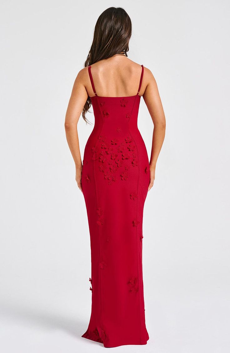 a woman wearing a red dress with cut out details on the side and back, looking down